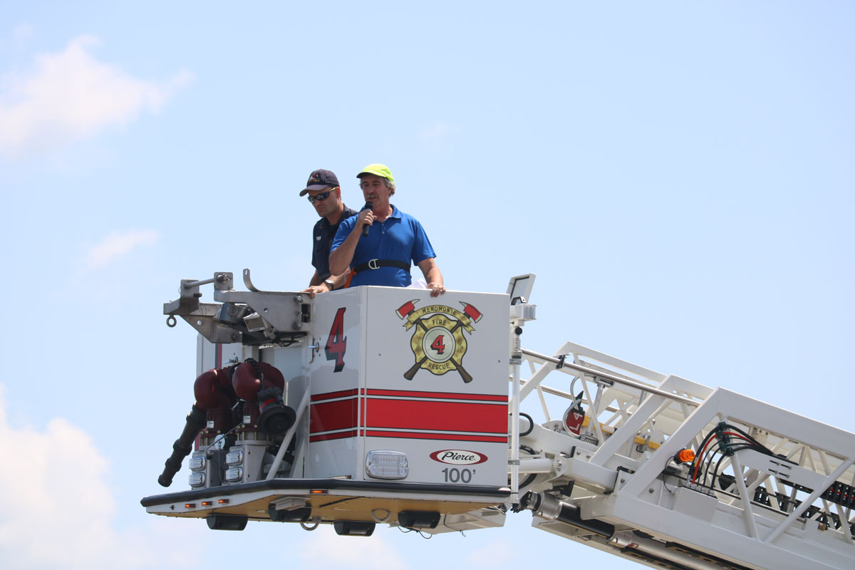 Mayor Randy Knaack singing national anthem from hook and ladder truck.